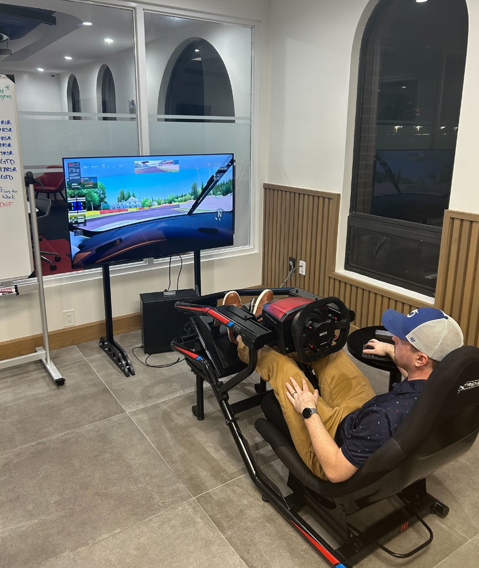 A BuyerBridge team member in the office racing simulator