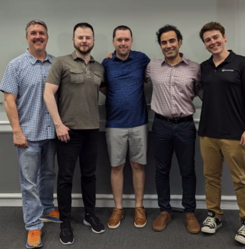 5 members of the BuyerBridge team standing arm in arm at the office